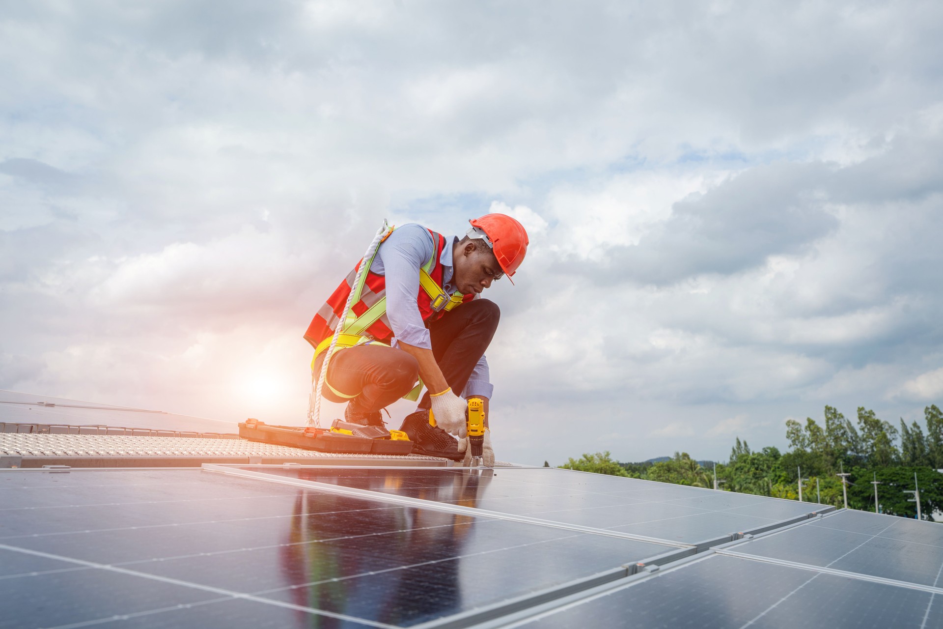 Solar panel technician with drill installing solar panels on roof factory.